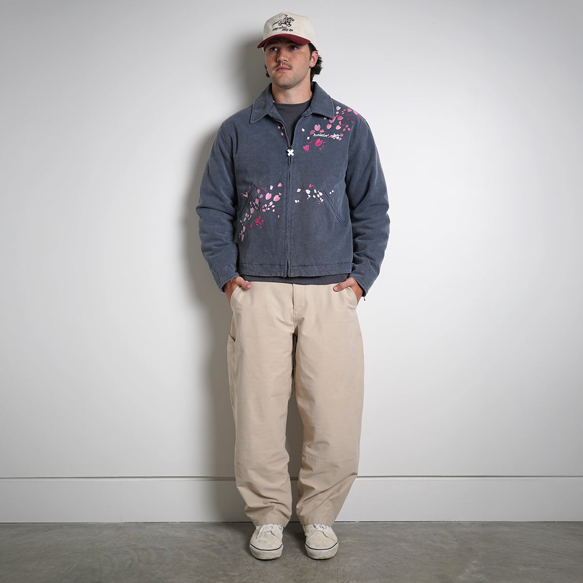 Washed navy Drum Island Jacket with scattered pink petals, partially zipped, front view on model