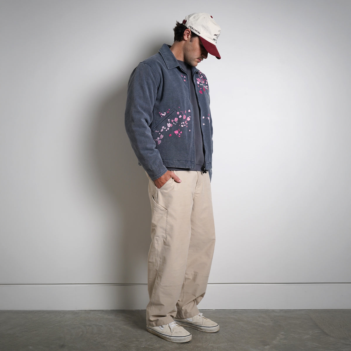 Washed navy Drum Island Jacket with scattered pink petals, partially zipped, side view on model