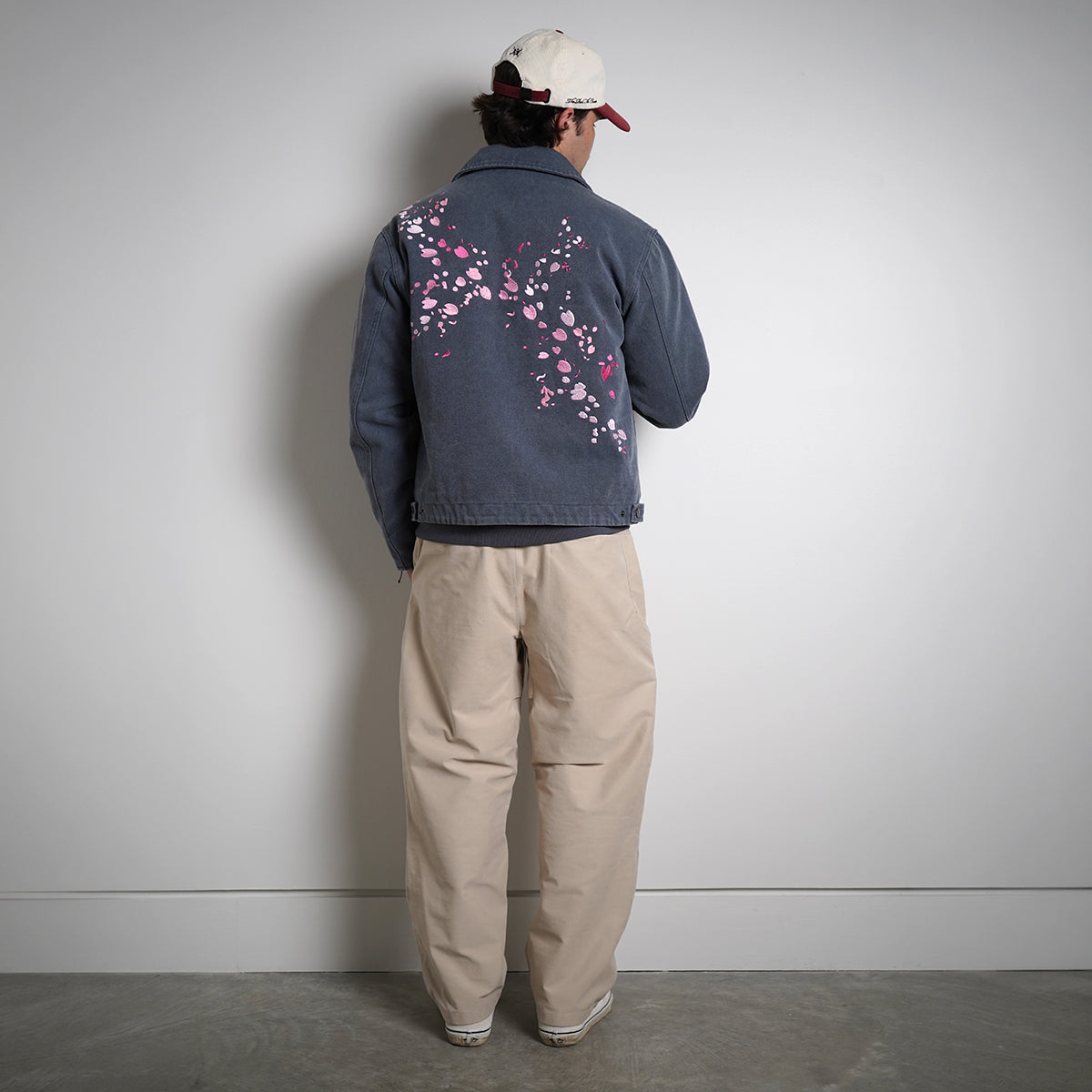 Washed navy Drum Island Jacket with scattered pink petals, partially zipped, back view on model