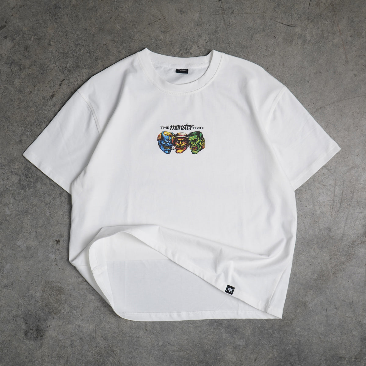 White t-shirt with colorful graphic design on a gray concrete surface