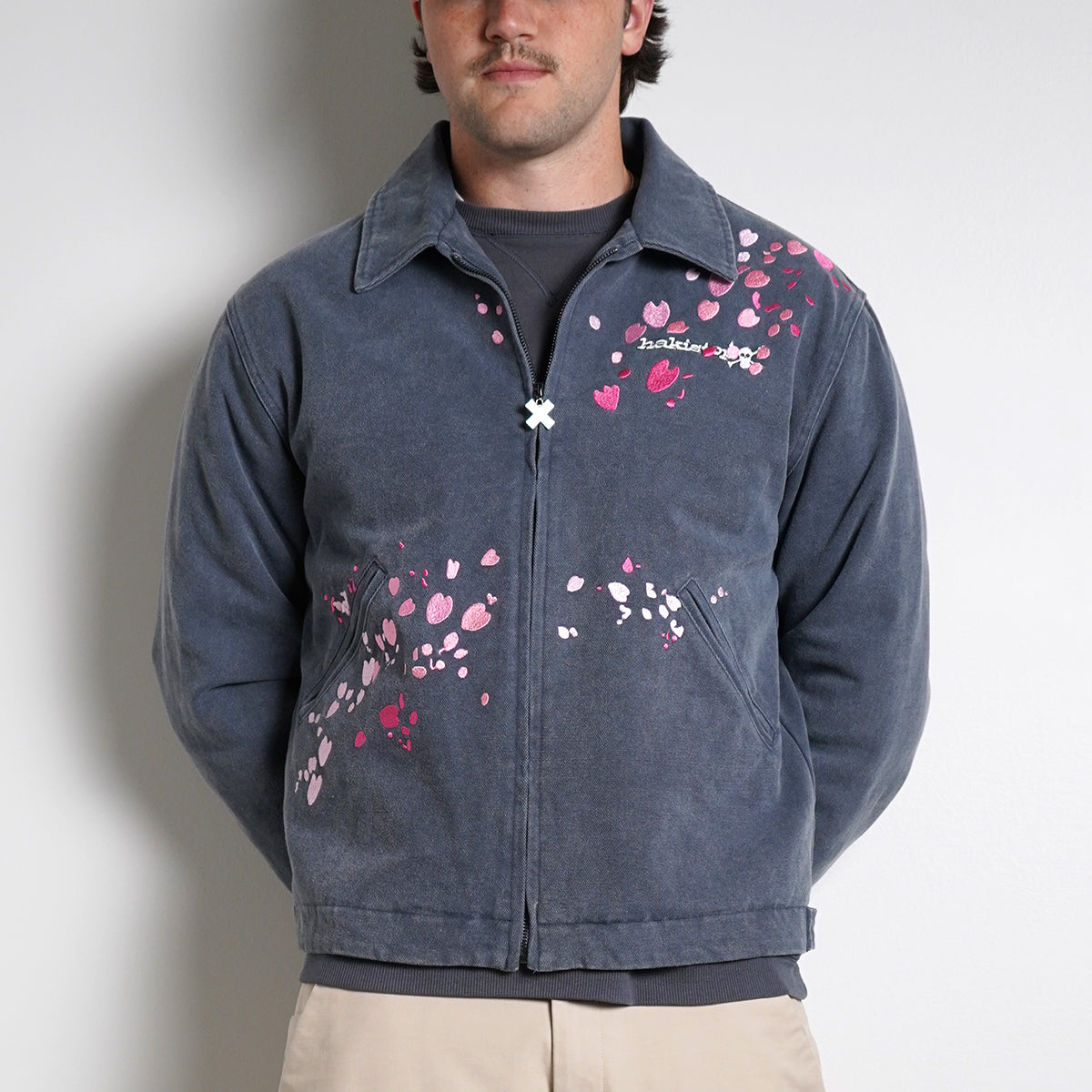 Washed navy Drum Island Jacket with scattered pink petals, partially zipped, front view on model