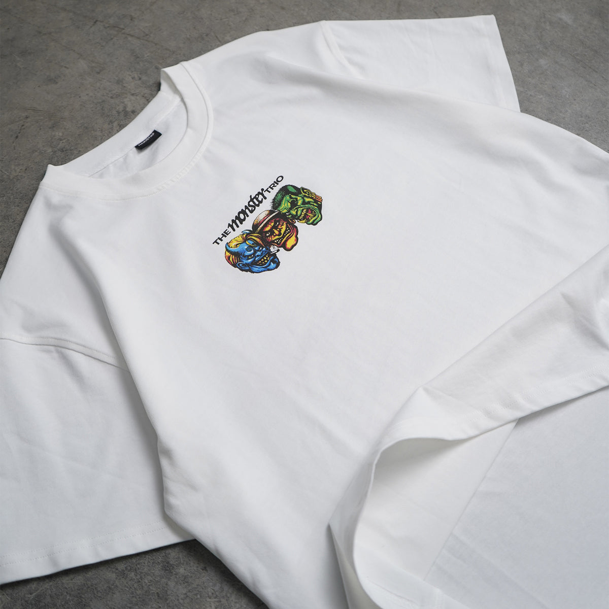 White sweatshirt with colorful graphic design on a gray surface