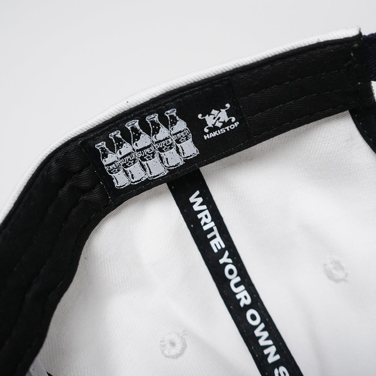Close-up of a cap with branding and text on a white background
