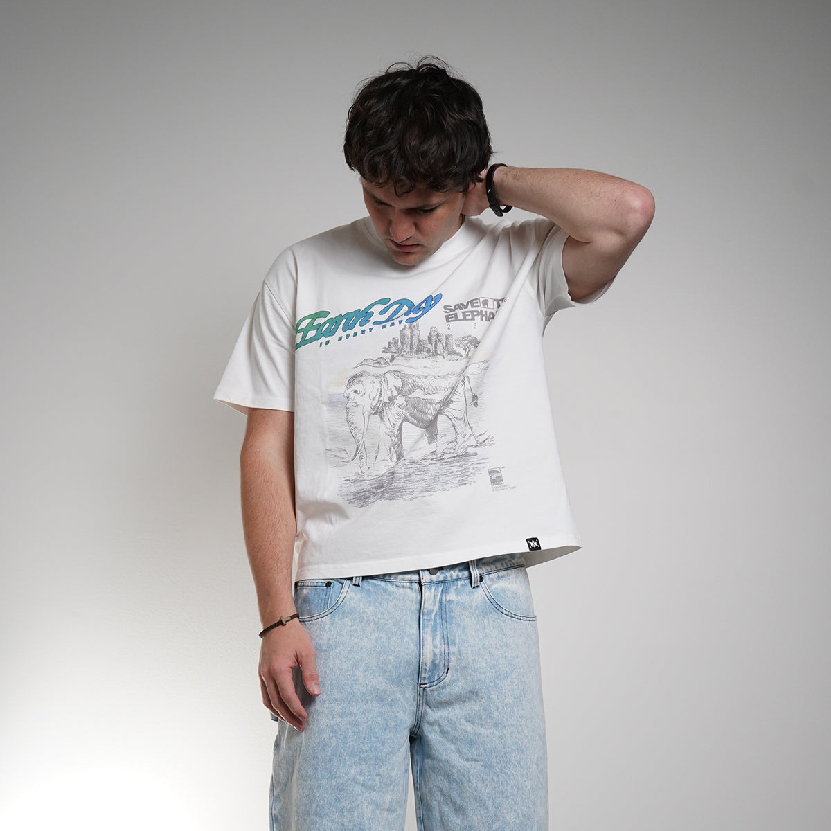 Person wearing a white graphic t-shirt and light blue jeans against a plain background