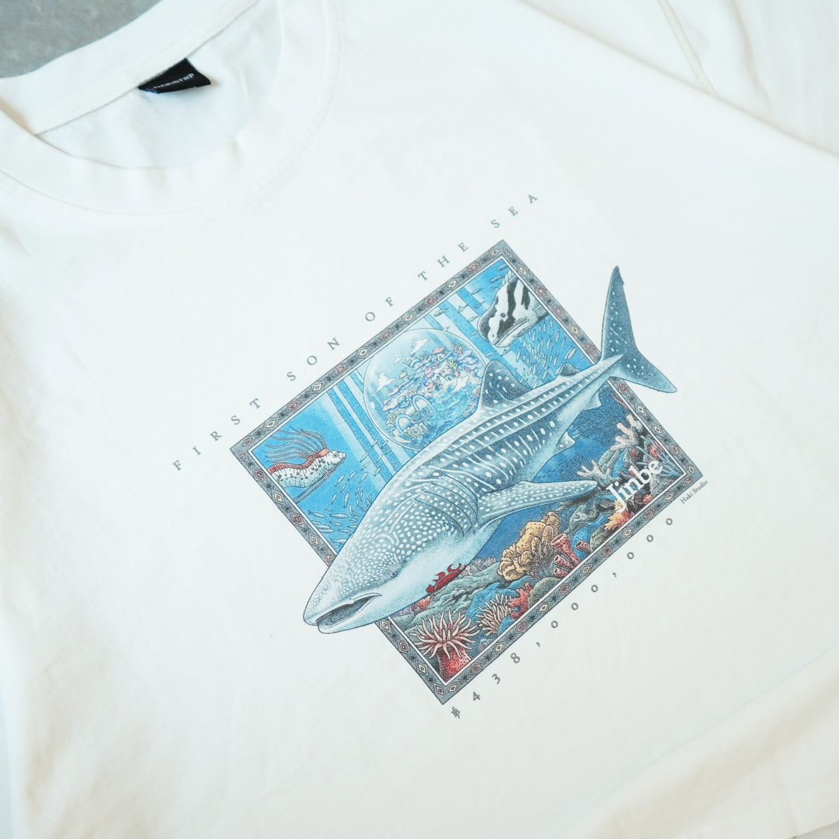 White shirt with a whale and ocean scene graphic on a white background