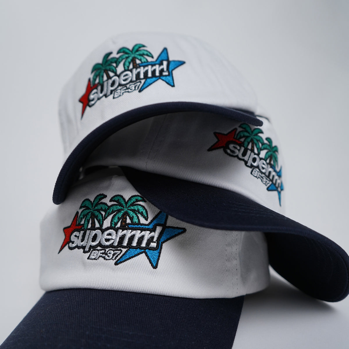 White and navy cap with colorful 'superrrrr!' branding on a light gray background