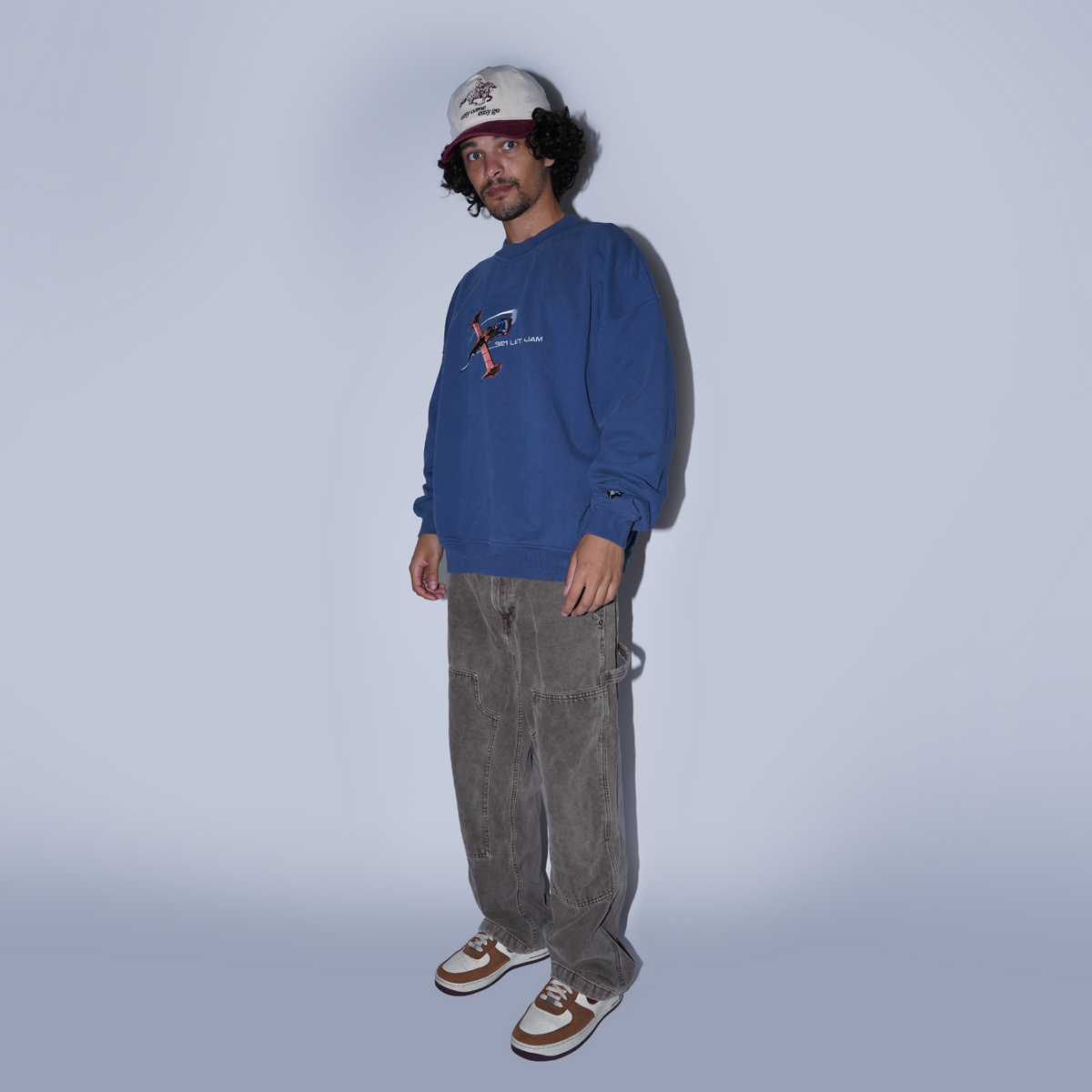 Person wearing a blue sweatshirt and gray pants on a plain background