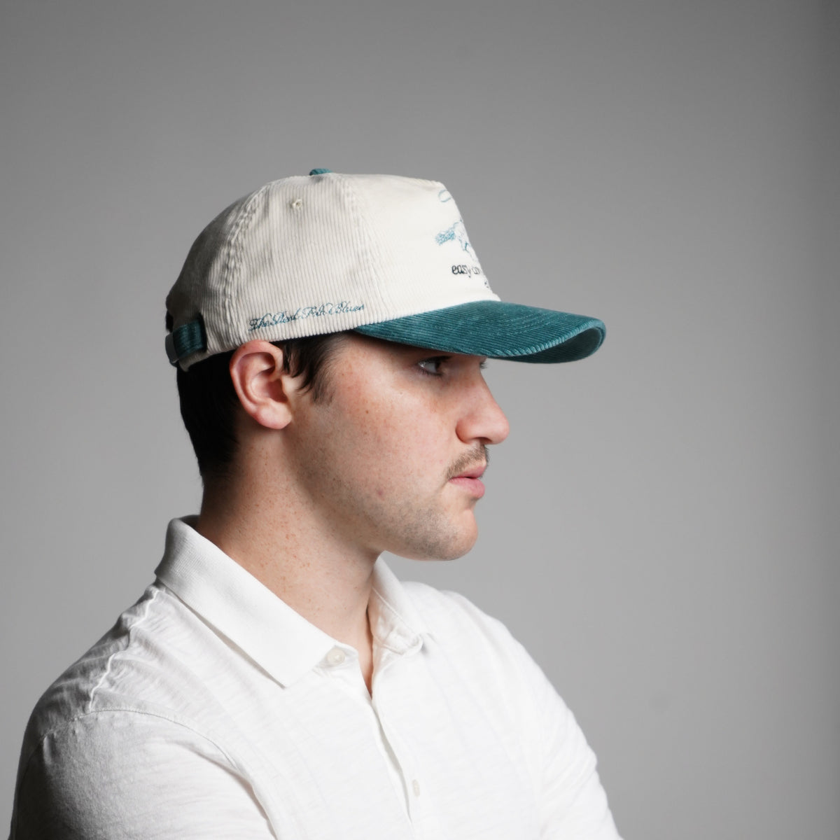Person wearing a white shirt and cap with a gray background