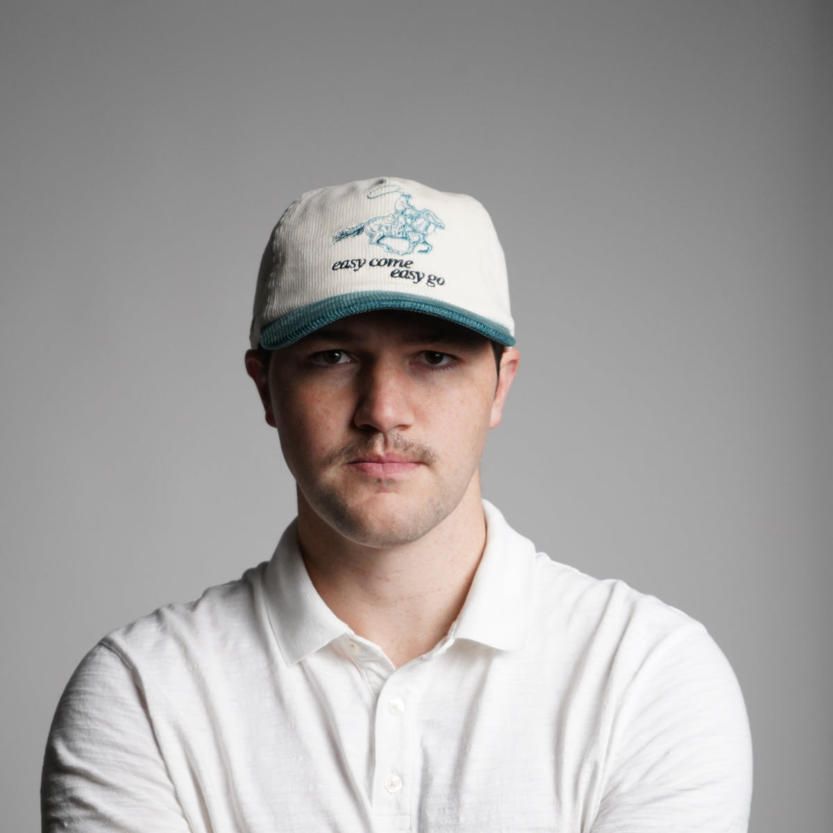 Person wearing a white t-shirt and cap on a gray background