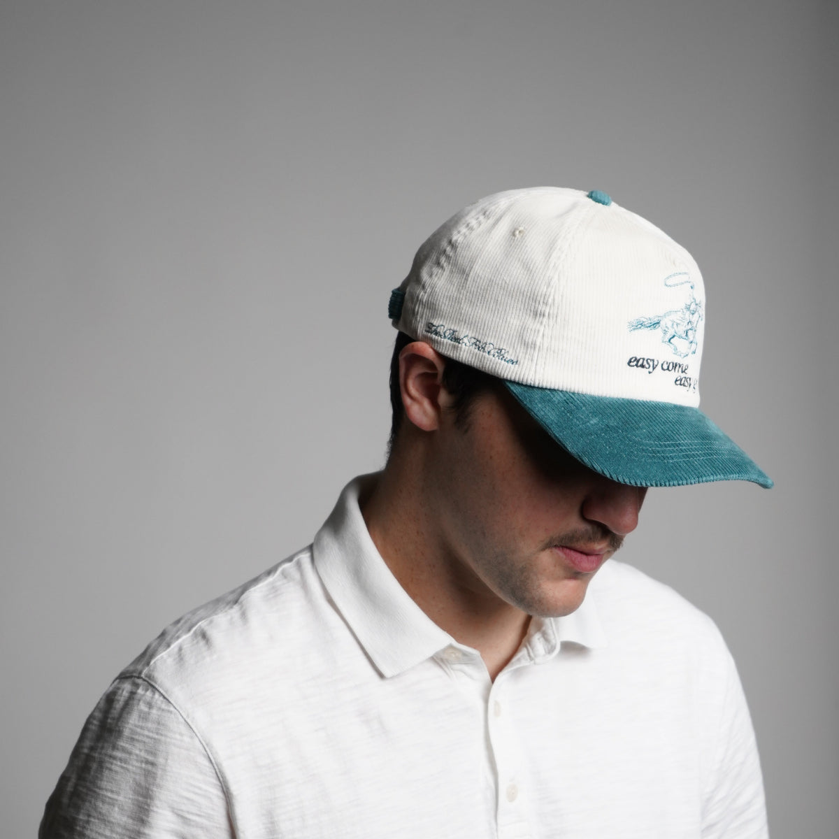 Person wearing a white cap with a logo on a gray background