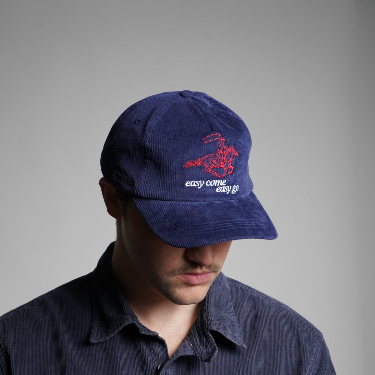 Person wearing a navy blue cap with a logo on a gray background