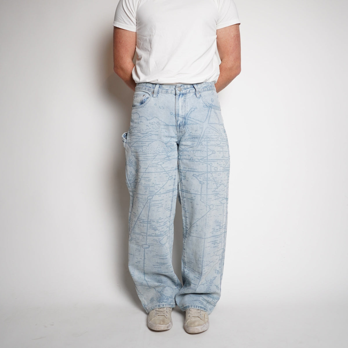 Person wearing light blue jeans and a white t-shirt on a plain background