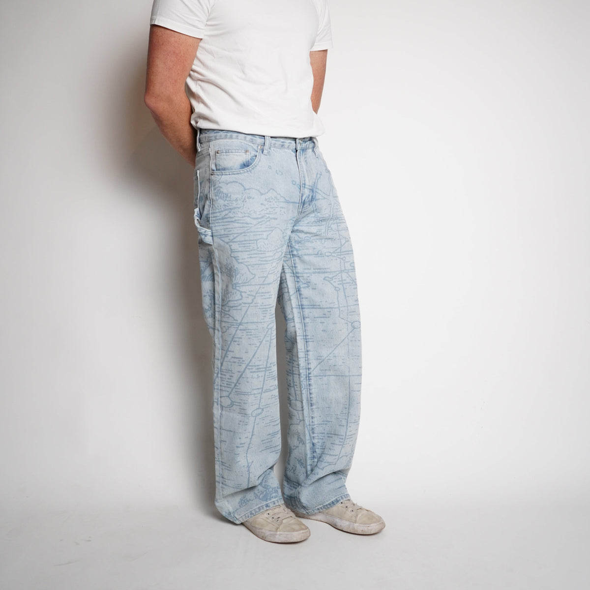 Person wearing light blue jeans and a white shirt on a plain background