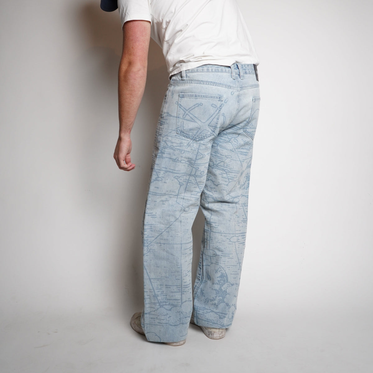 Person wearing light blue jeans and a white t-shirt on a plain background