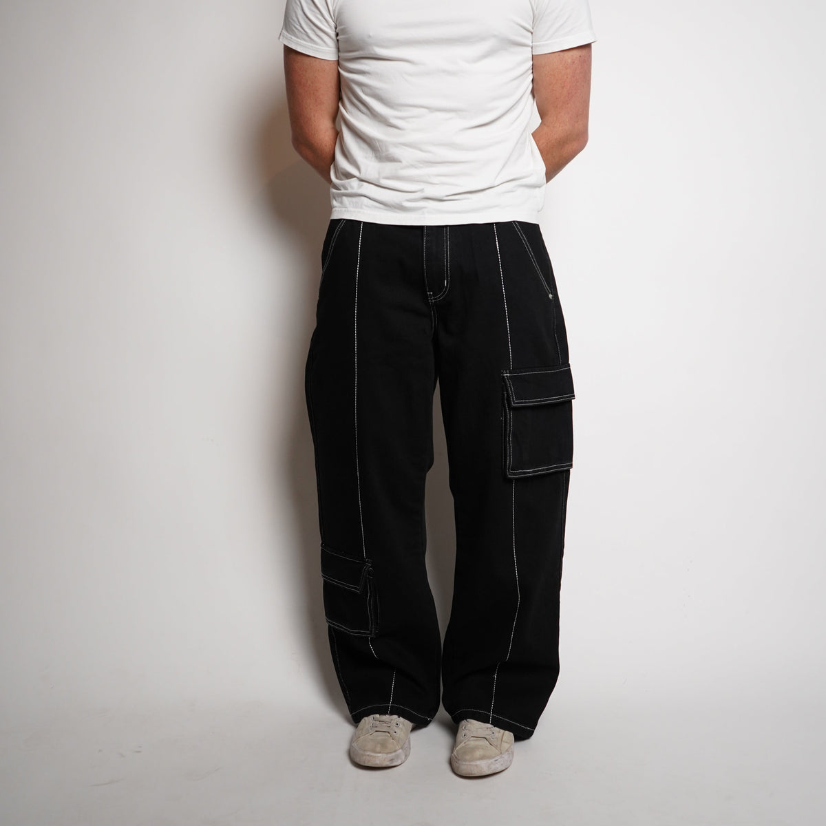 Person wearing a white shirt and black pants on a plain background