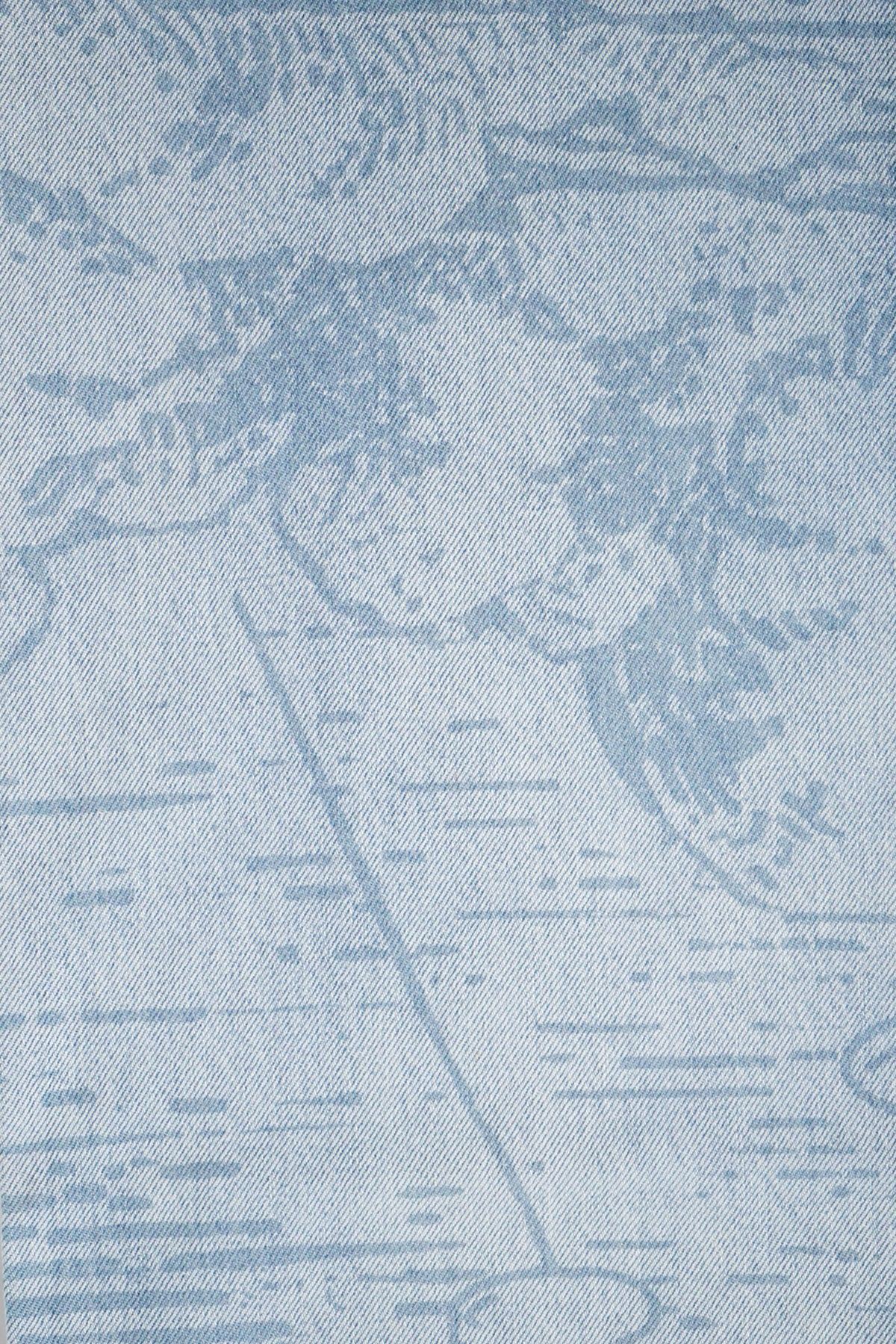 Close-up of the Grand Line Pants light blue denim fabric with a faded, darker blue printed map-like graphic of abstract landmasses and horizontal dashes