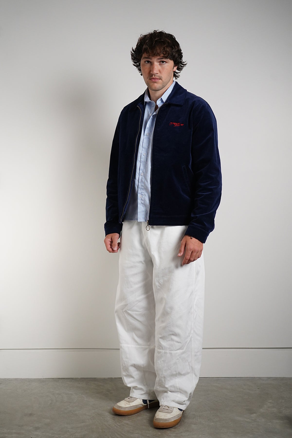 Navy Queen of Curses Jacket with red embroidered logo, front view on model with blue shirt.