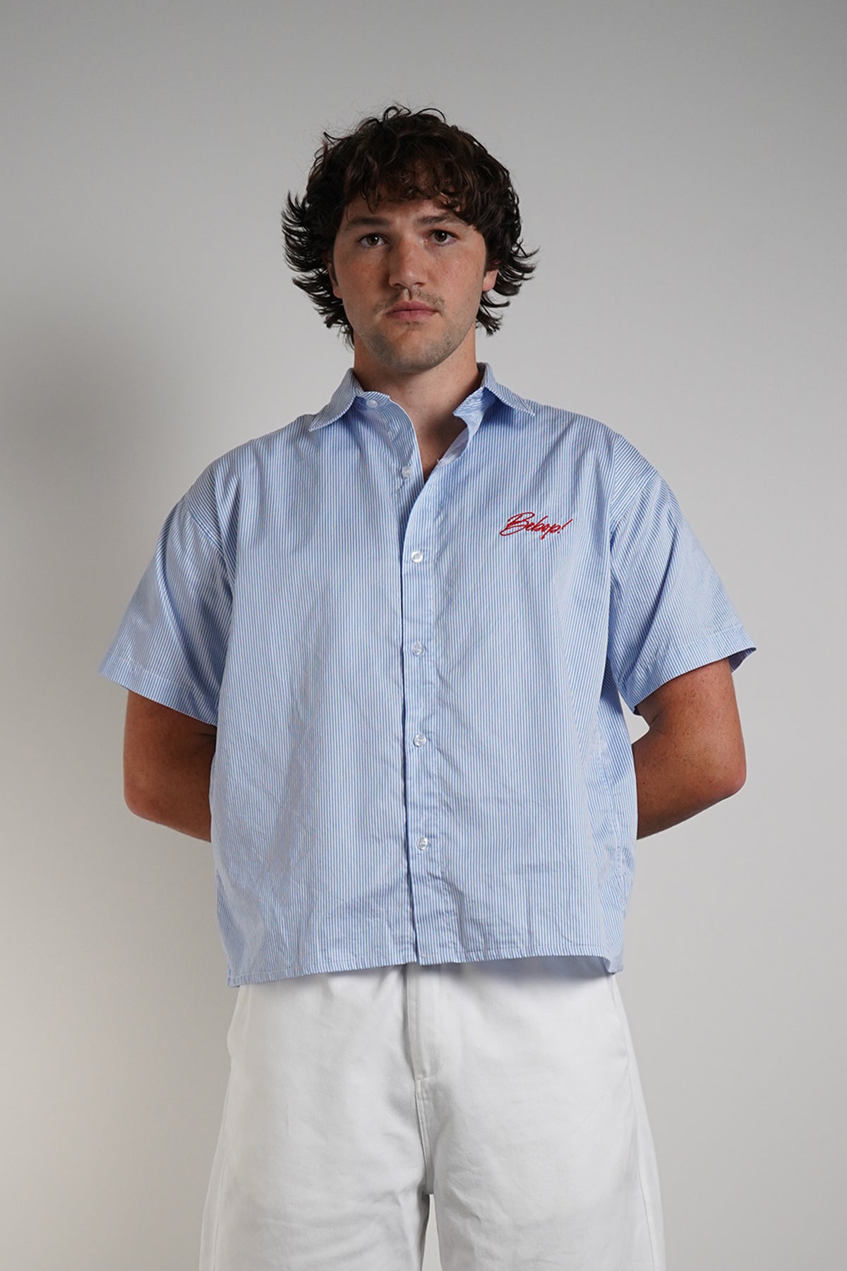 Bebop Work Shirt in light blue pinstripe with red embroidered logo, front view on model.