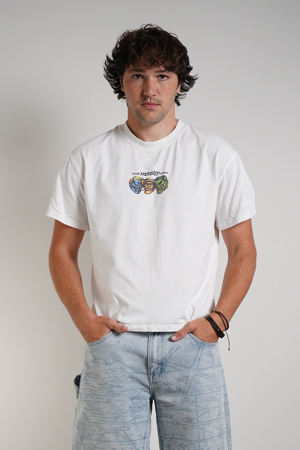 White Monster Trio Tee with three monster faces chest graphic, front view on model