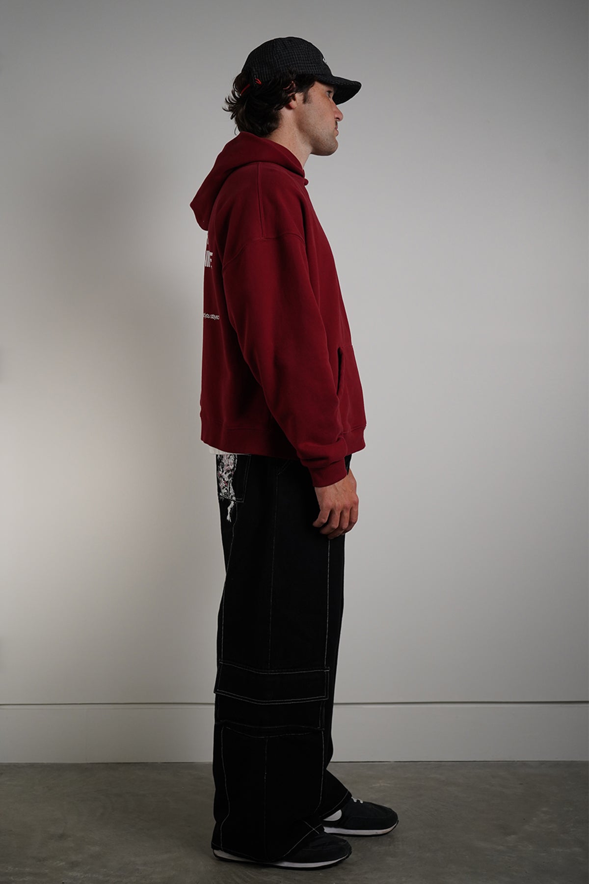 Black Divine Dogs Pants with white contrast stitching and cargo pockets, side view on model