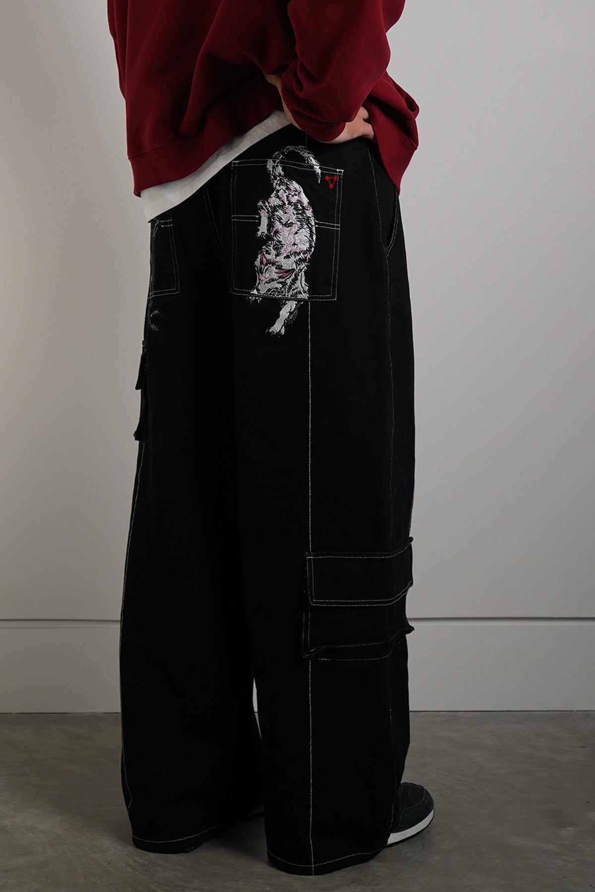 Black Divine Dogs Pants with embroidered dog graphics on back pockets, back view on model