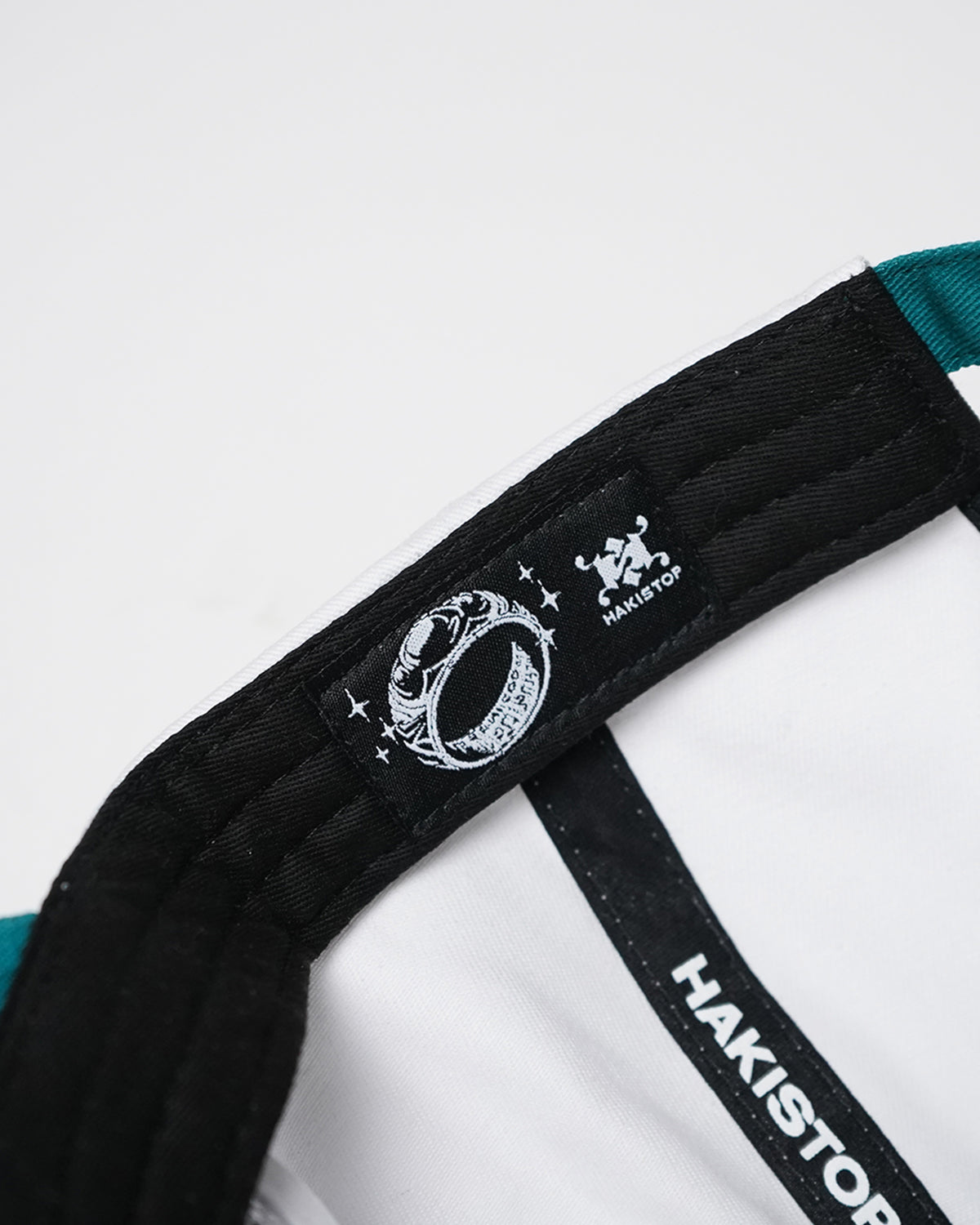 Interior of the Greed Island Hat showing black sweatband label with white ring graphic and HAKISTOP logo