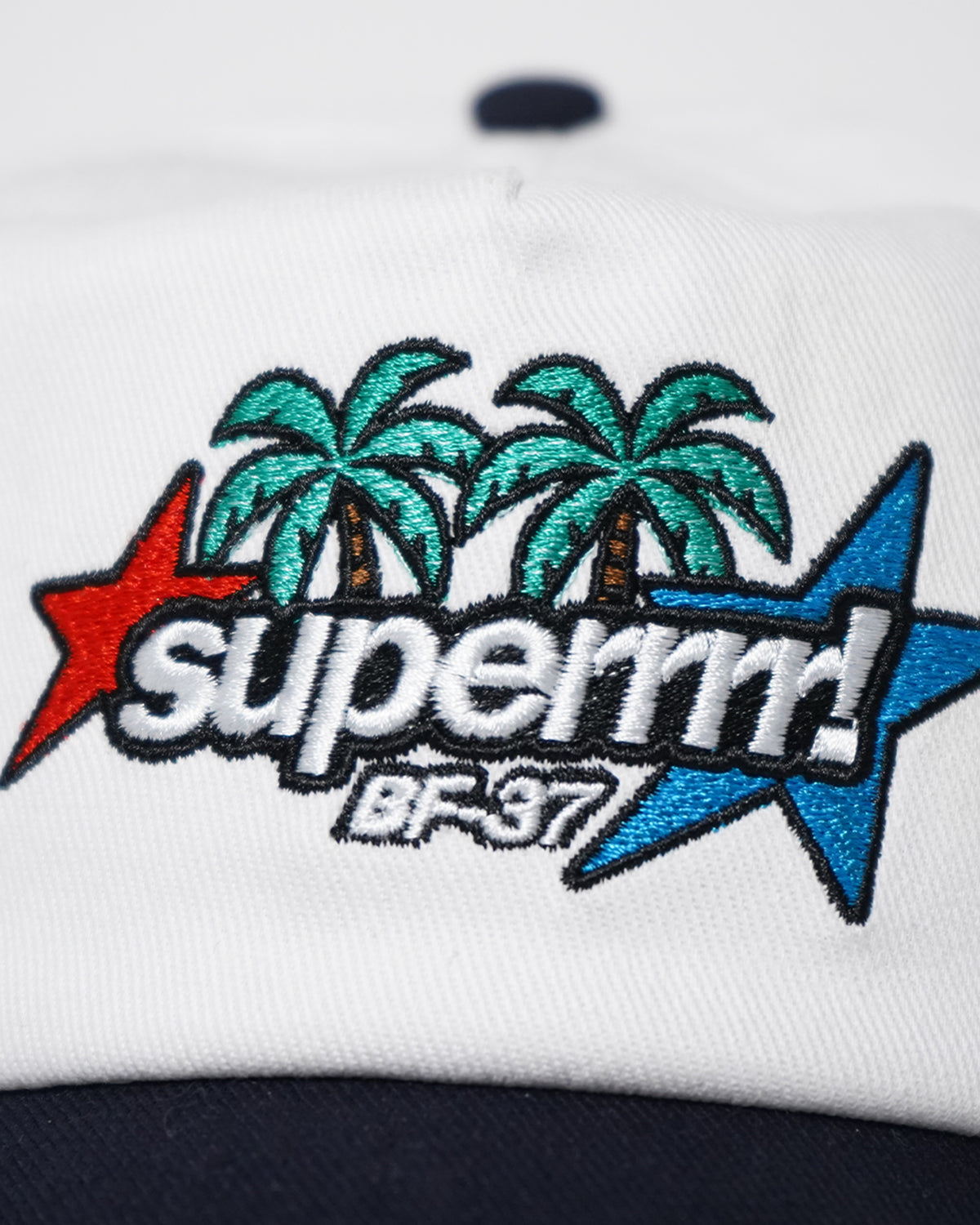 Close-up of the Superrrr Hat embroidery with palm trees, red and blue stars and superrrr! BF-37 text