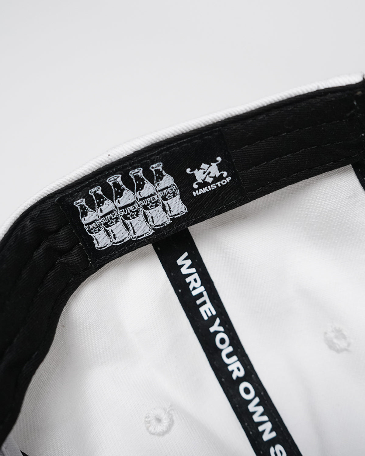 Interior of the Superrrr Hat showing HAKISTOP label, soda-bottle label and WRITE YOUR OWN taping