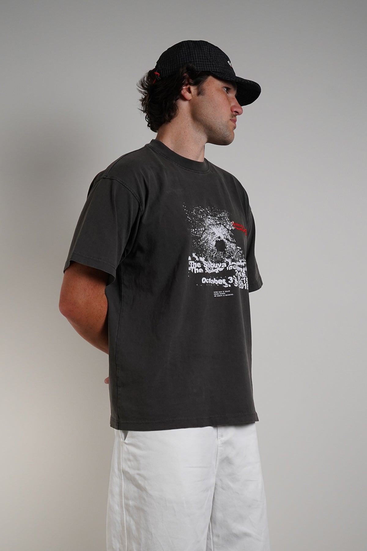 Charcoal Shibuya Incident Tee with dispersing graphic and date print, side view on model.