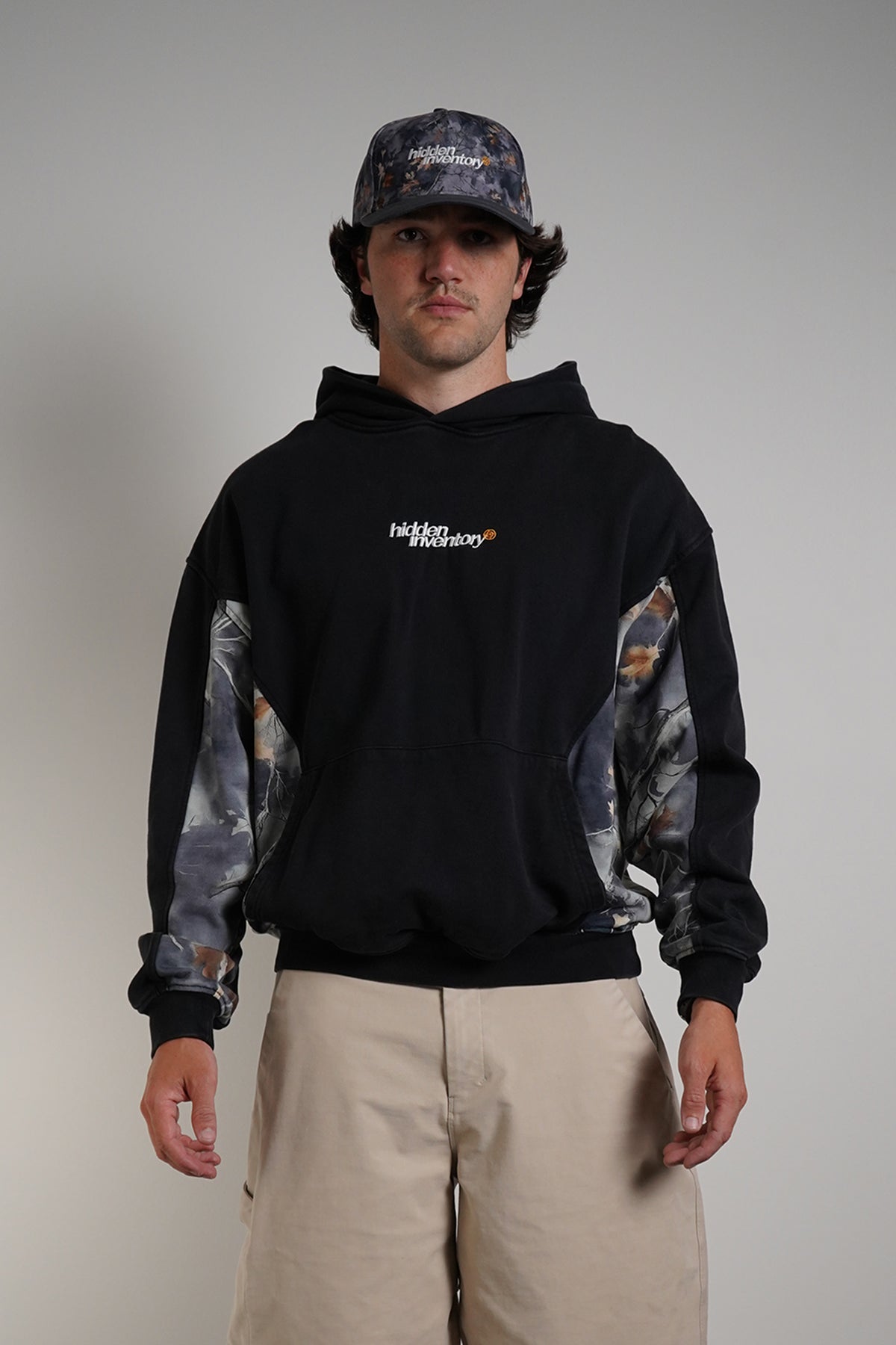 Hidden Inventory Bundle styled with black hoodie, cargo pants, and matching cap on model.