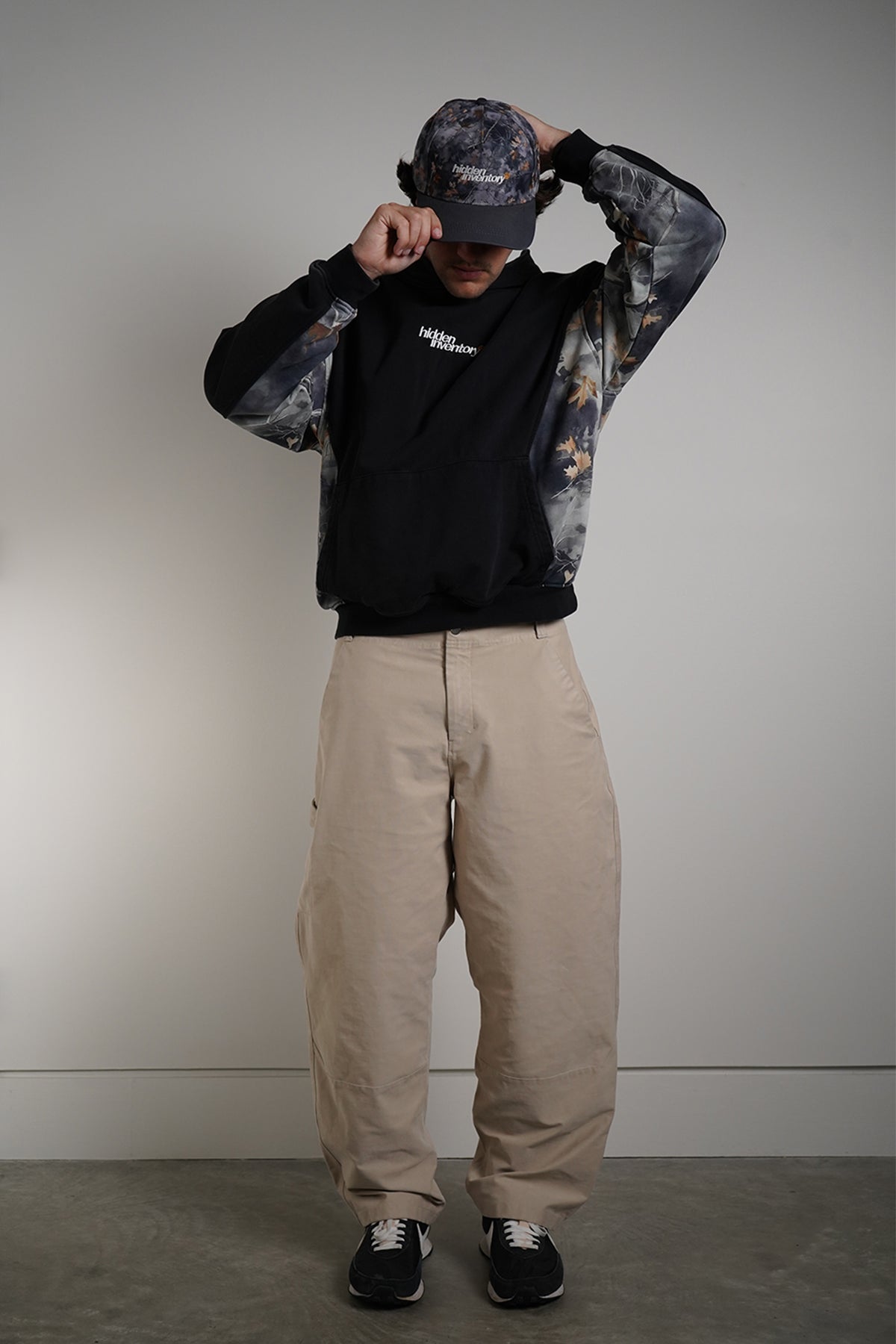 Hidden Inventory Bundle styled with black hoodie, cargo pants, and matching cap on model.