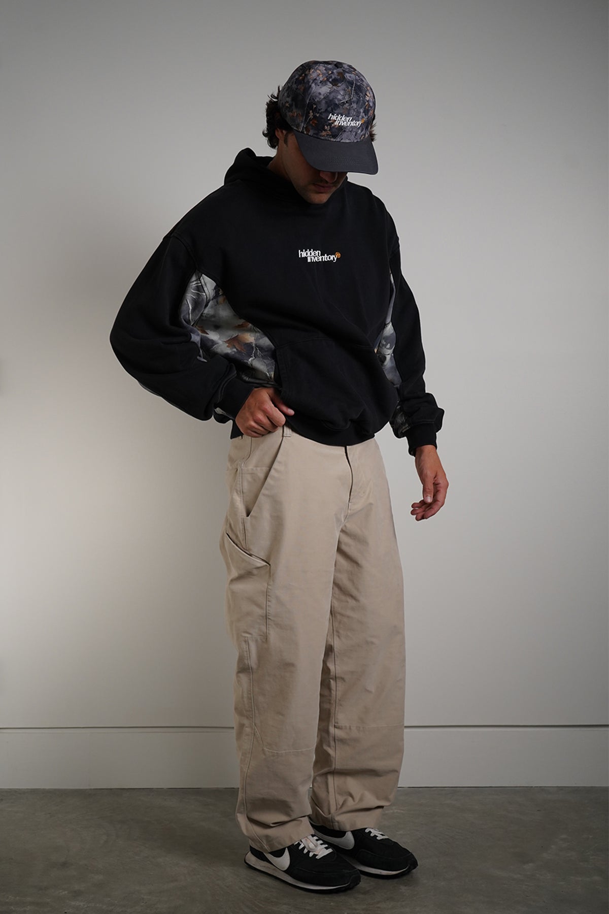 Hidden Inventory Bundle styled with black hoodie, cargo pants, and matching cap on model.