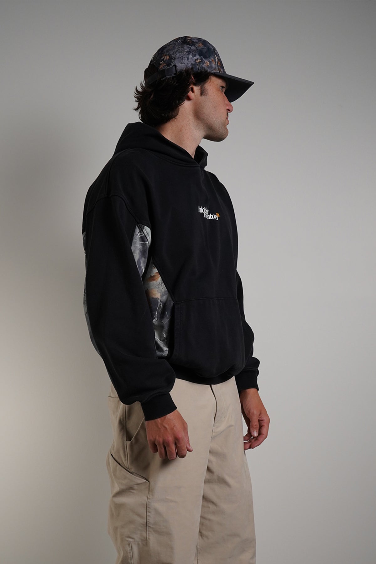Hidden Inventory Bundle styled with black hoodie, cargo pants, and matching cap on model.