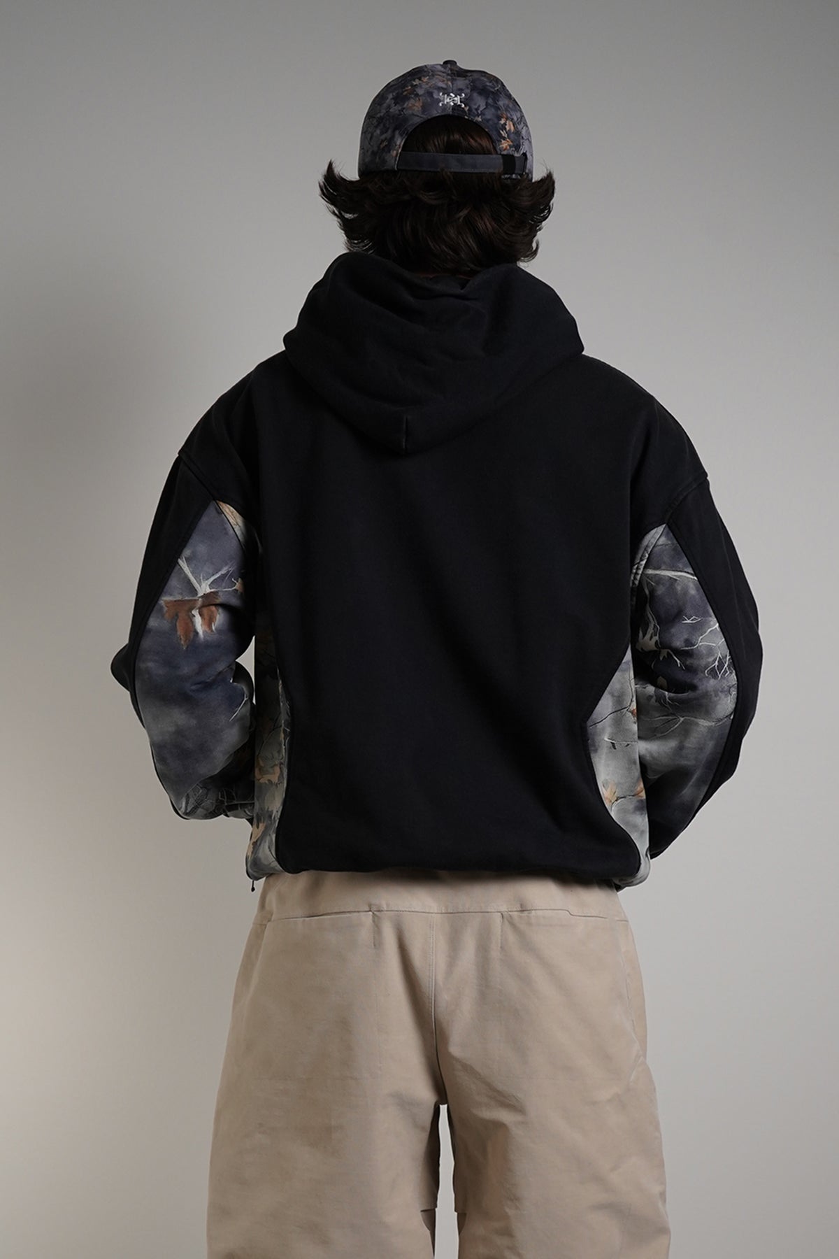 Hidden Inventory Bundle styled with black hoodie, cargo pants, and matching cap on model, back view.