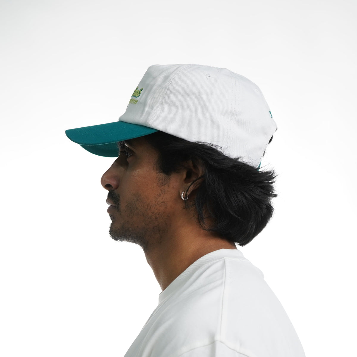 Person wearing a white cap with a green brim on a white background