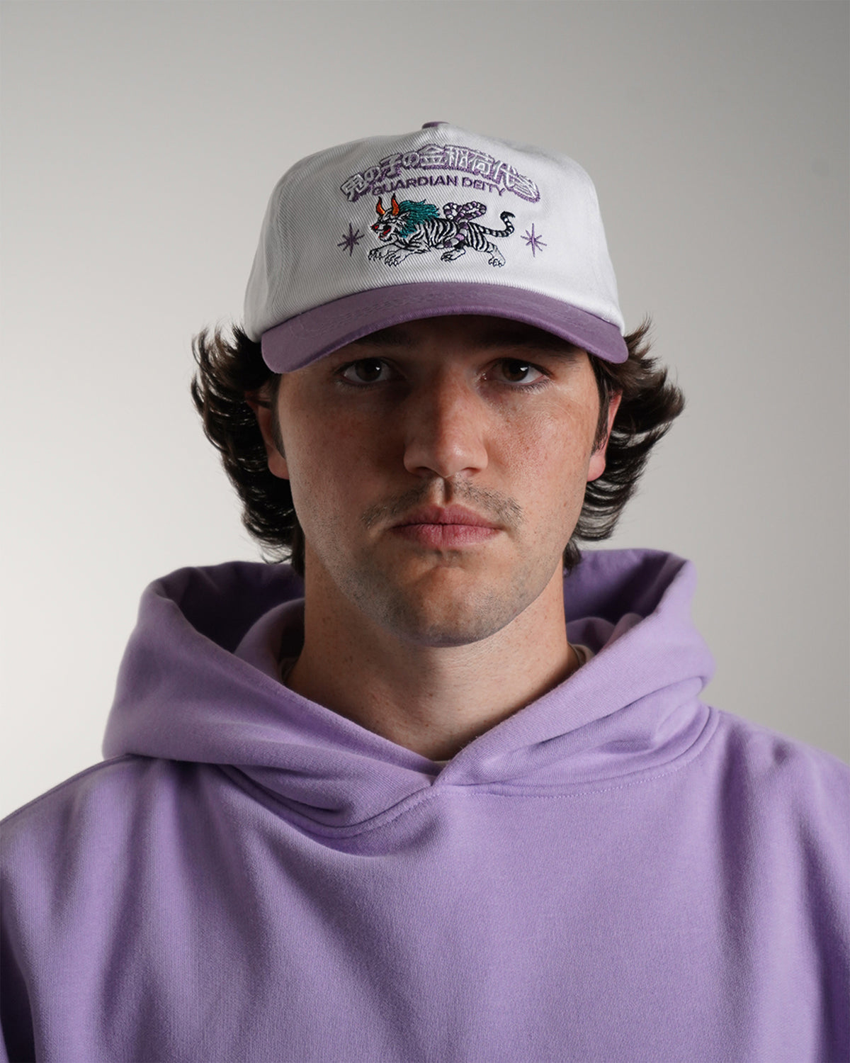 Guardian Deity Hat in white and purple with embroidered tiger graphic, front view on model.