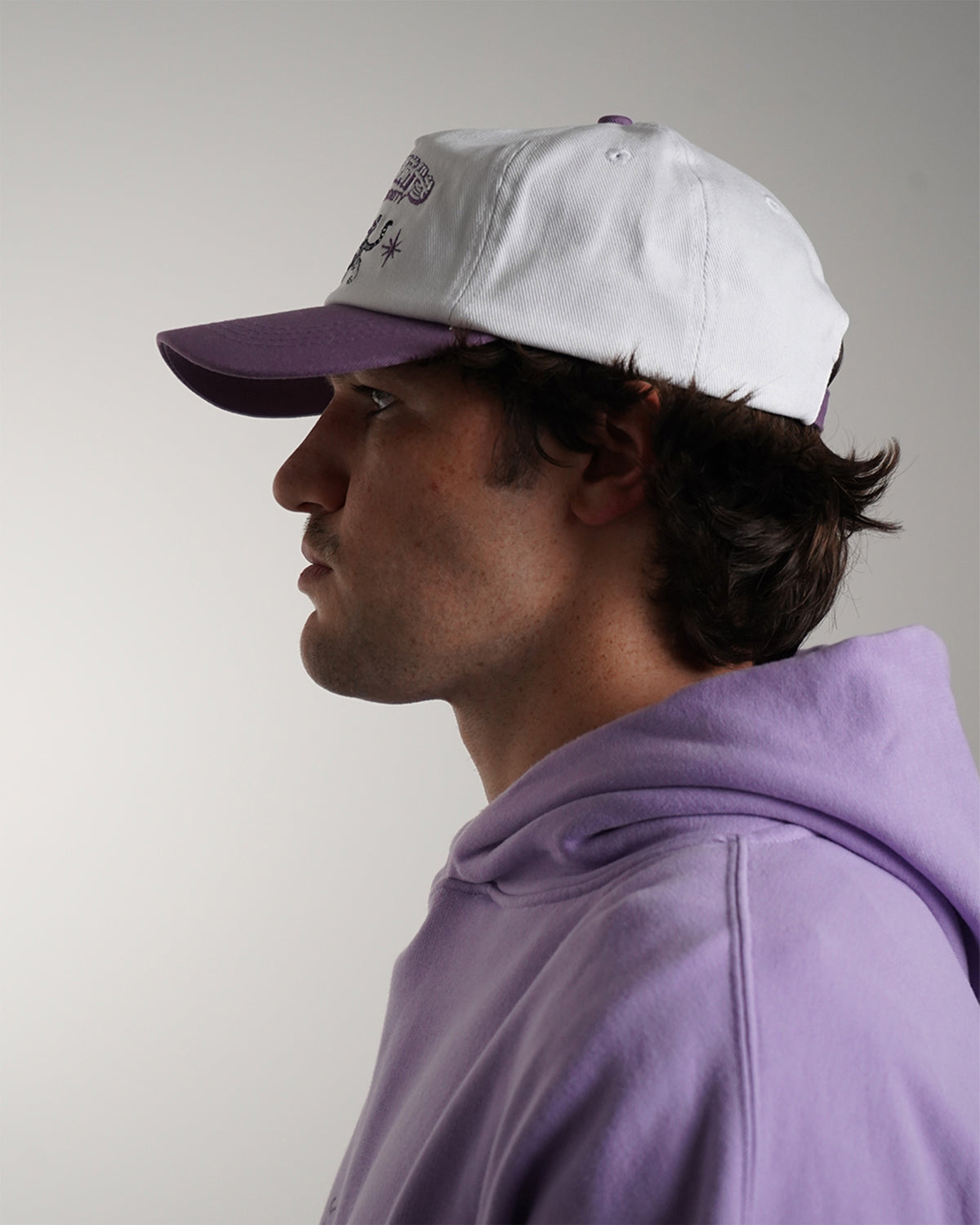 Guardian Deity Hat in white and purple with embroidered tiger graphic, side view on model.