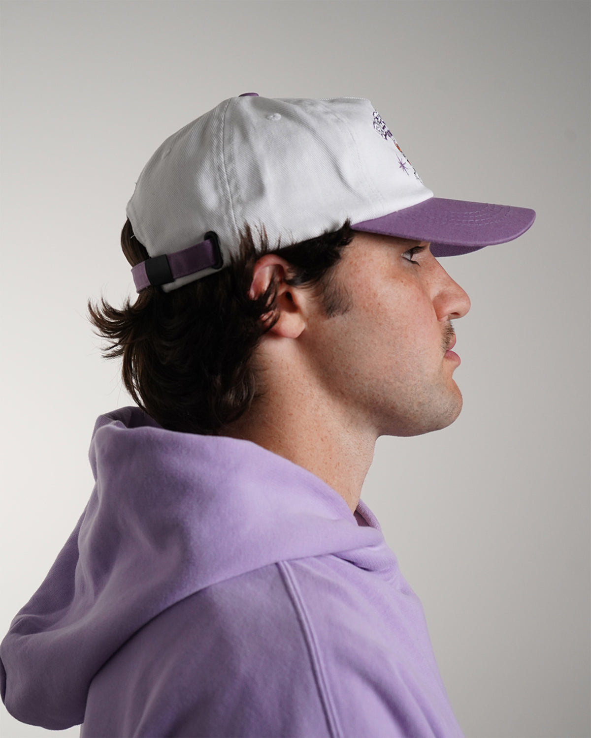 Guardian Deity Hat in white and purple with embroidered tiger graphic, side view on model.