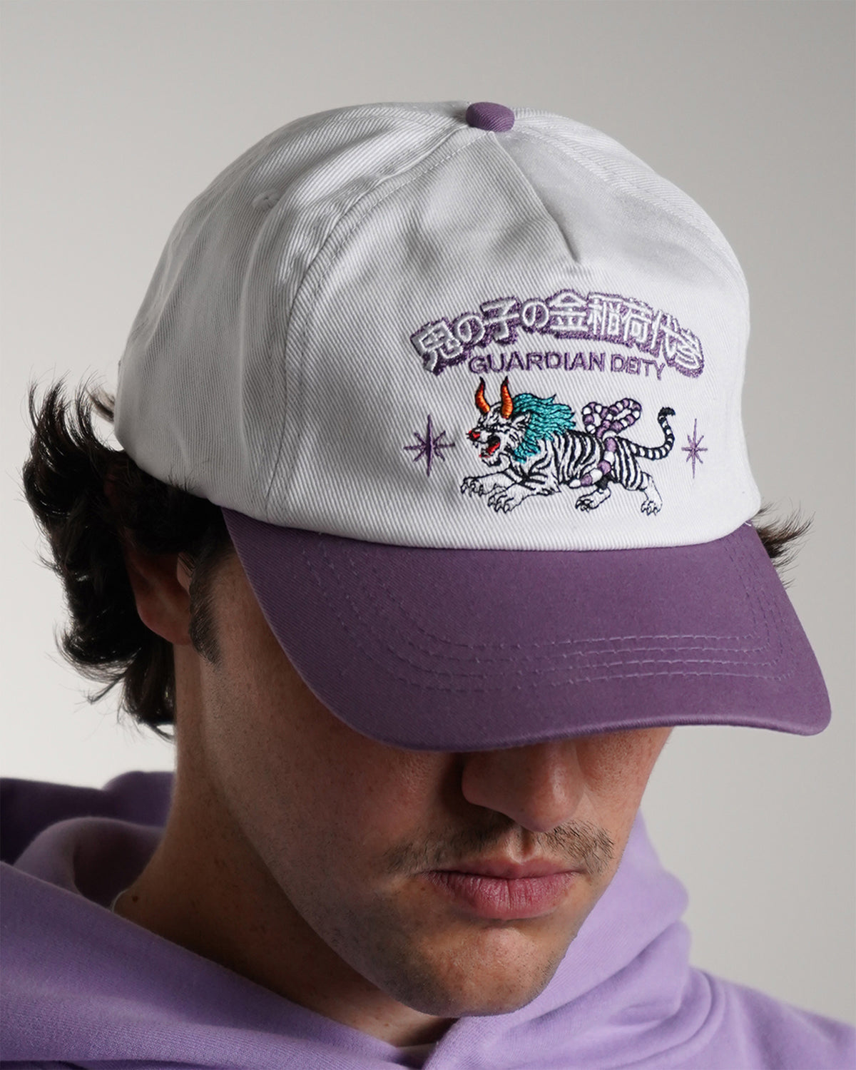 Guardian Deity Hat in white and purple with embroidered tiger graphic, front view on model.