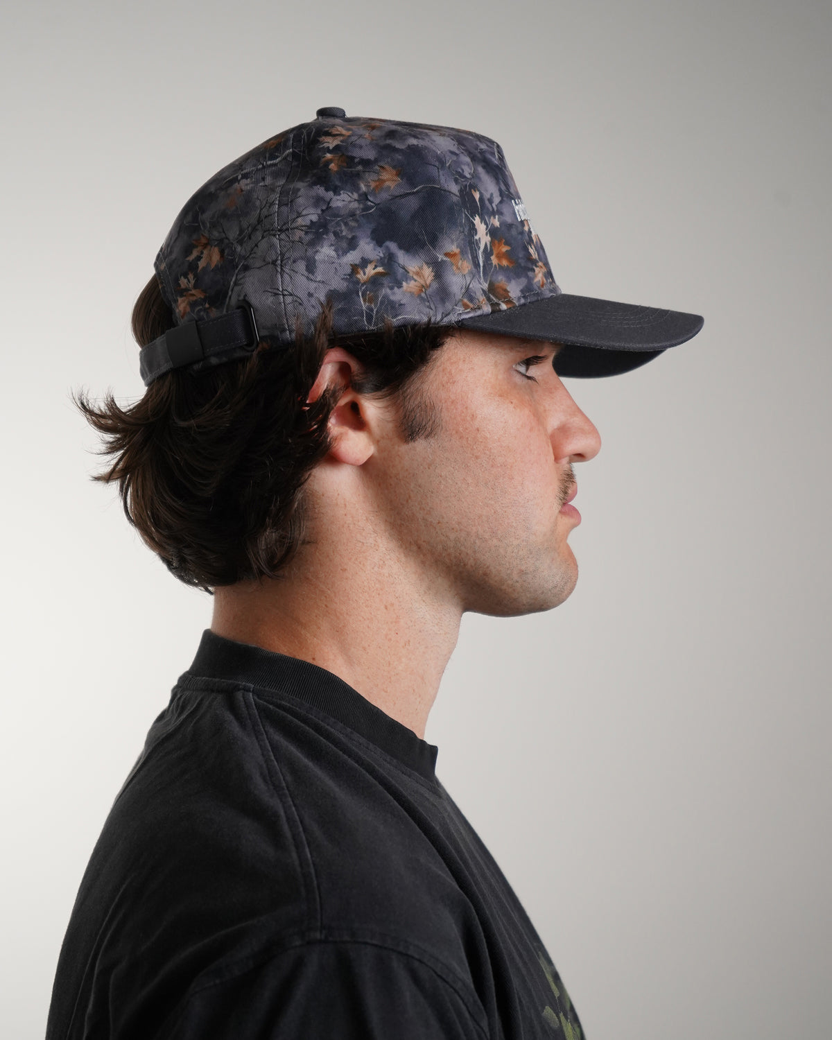Hidden Inventory Hat in grey camo with embroidered logo, side view in model