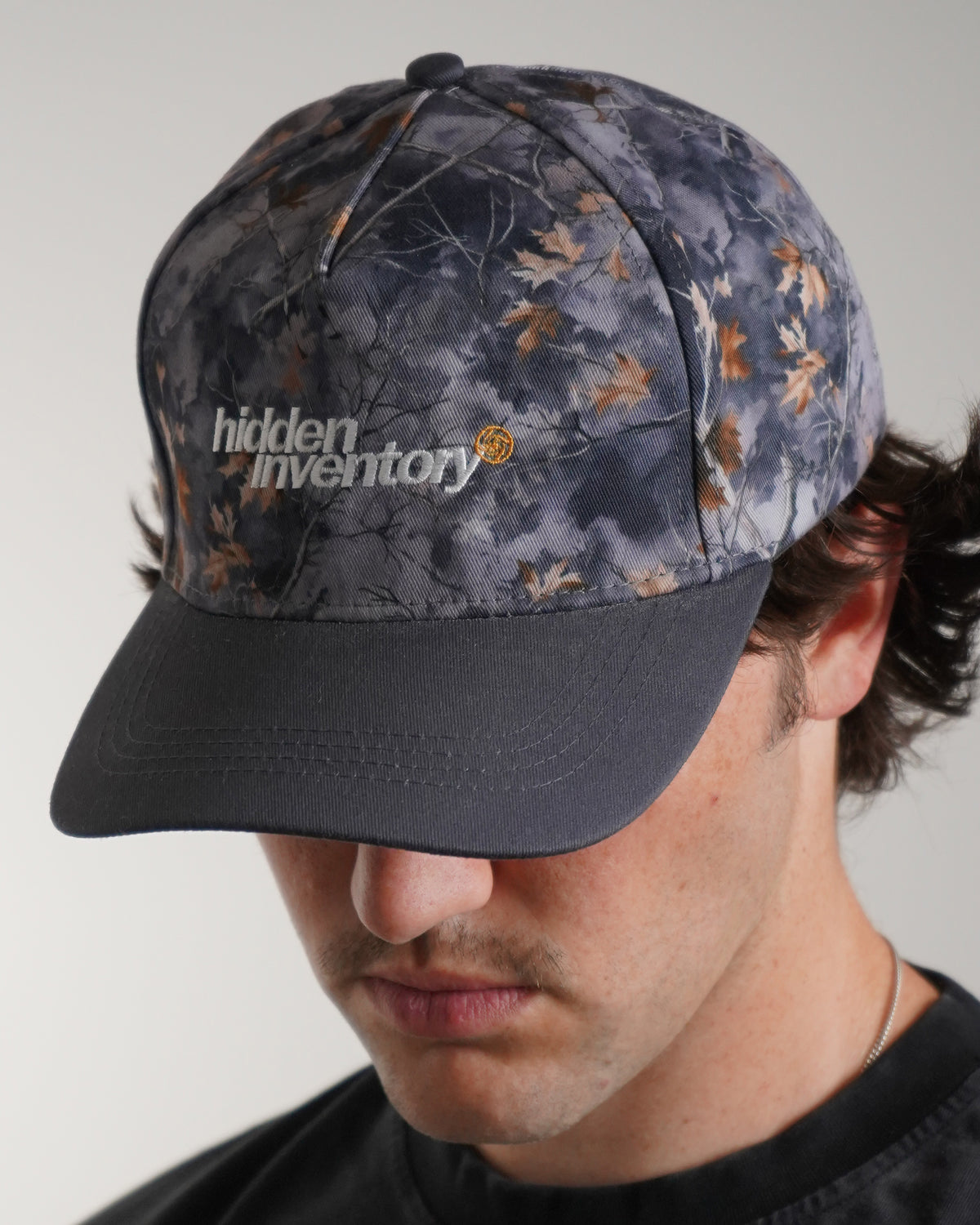 Hidden Inventory Hat in grey camo with embroidered logo, front view in model