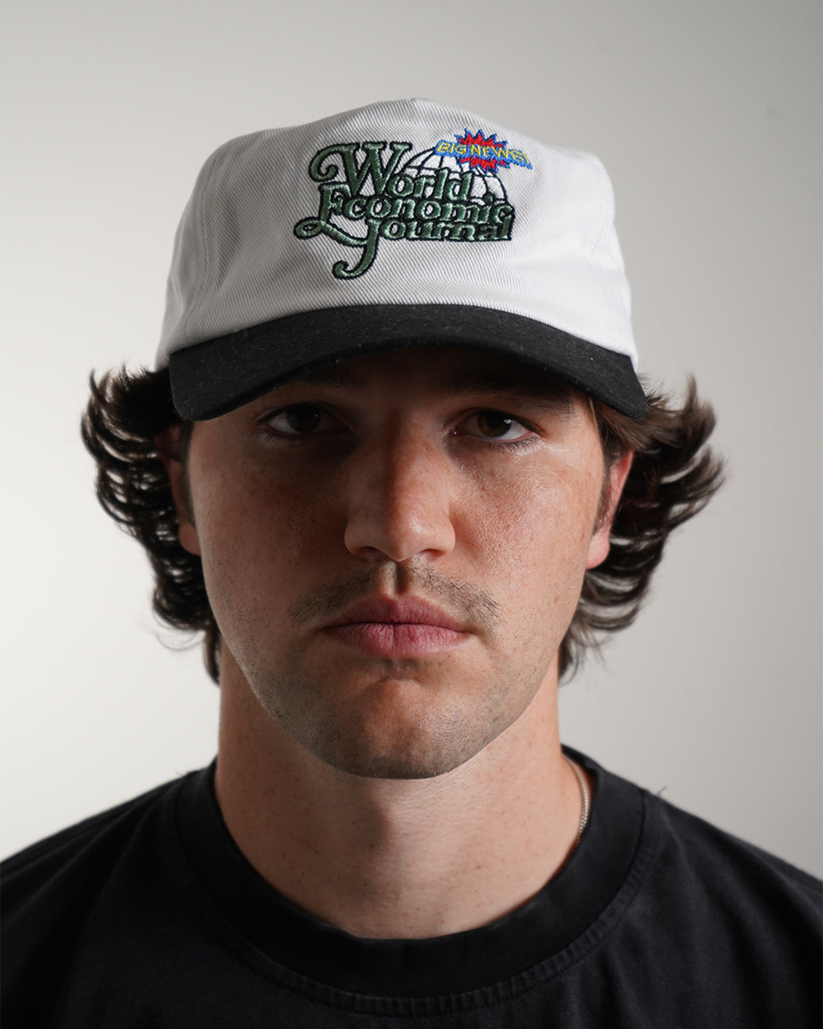 White Big News! Hat with green embroidered logo, front view on model 