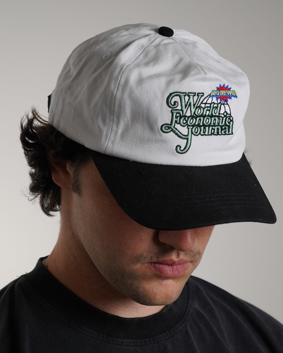White Big News! Hat with green embroidered logo, side view on model 