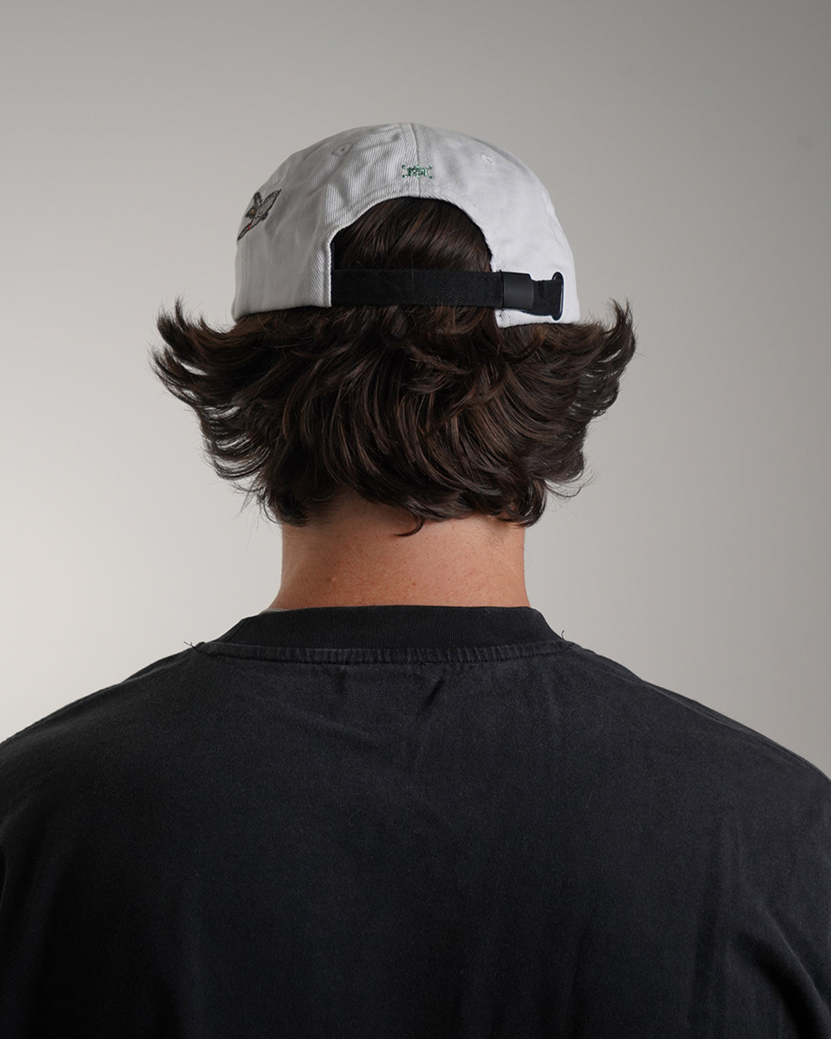 White Big News! Hat with green embroidered logo, back view on model 