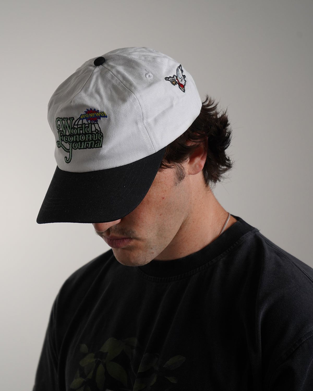 White Big News! Hat with green embroidered logo, side view on model 