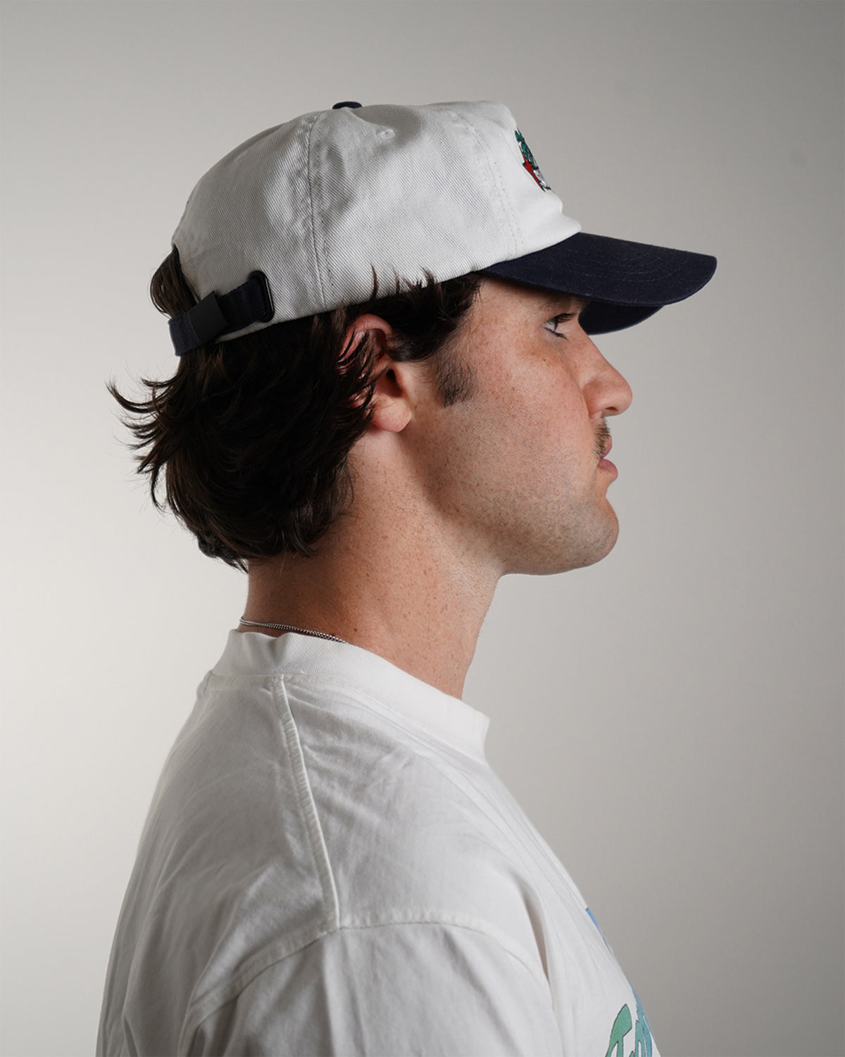Side view modeled white Superrrr Hat with navy brim and embroidered palm trees, stars and superrrr! logo