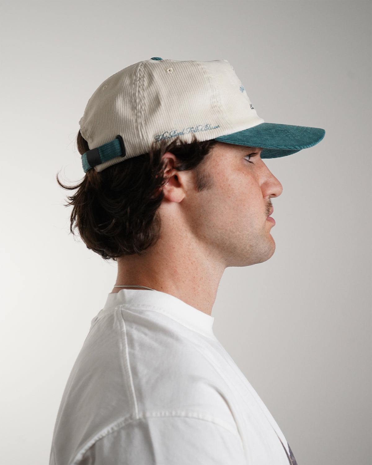 Easy Come Easy Go Hat (Tennis Green) in cream with teal cowboy graphic and brim, side view on model
