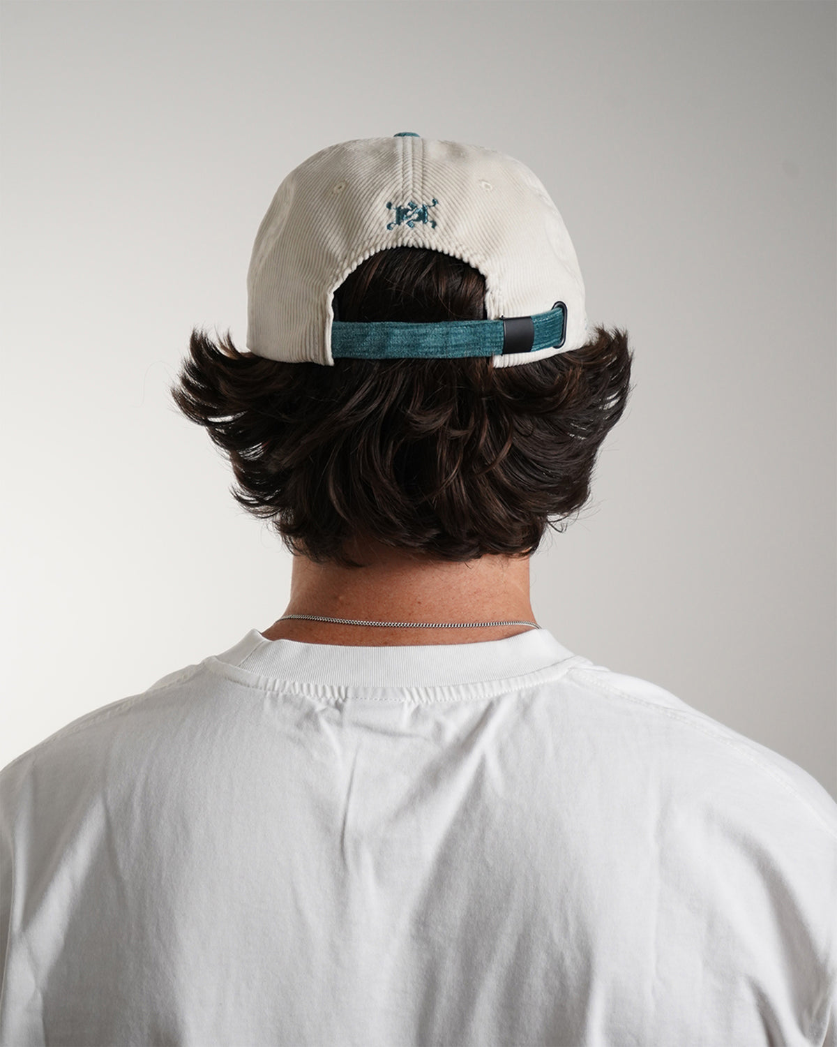 Easy Come Easy Go Hat in white with teal back strap, back view on model.