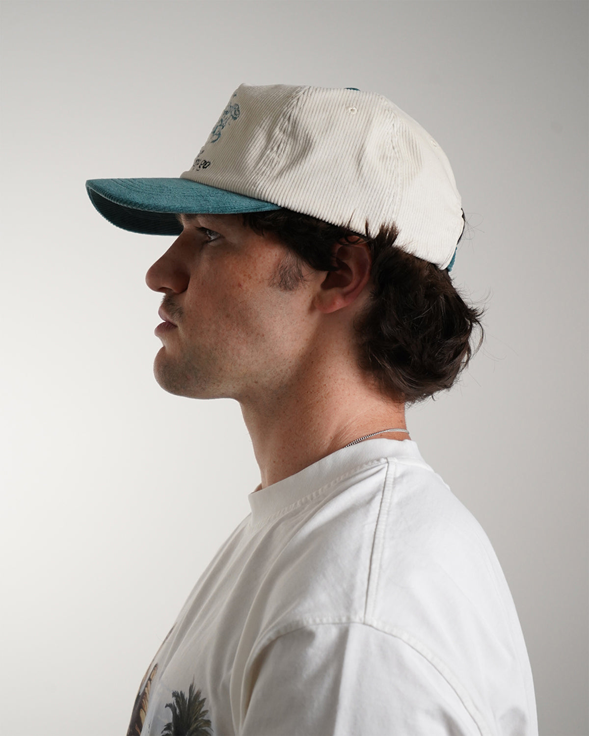 Easy Come Easy Go Hat (Tennis Green) in cream with teal cowboy graphic and brim, side view on model