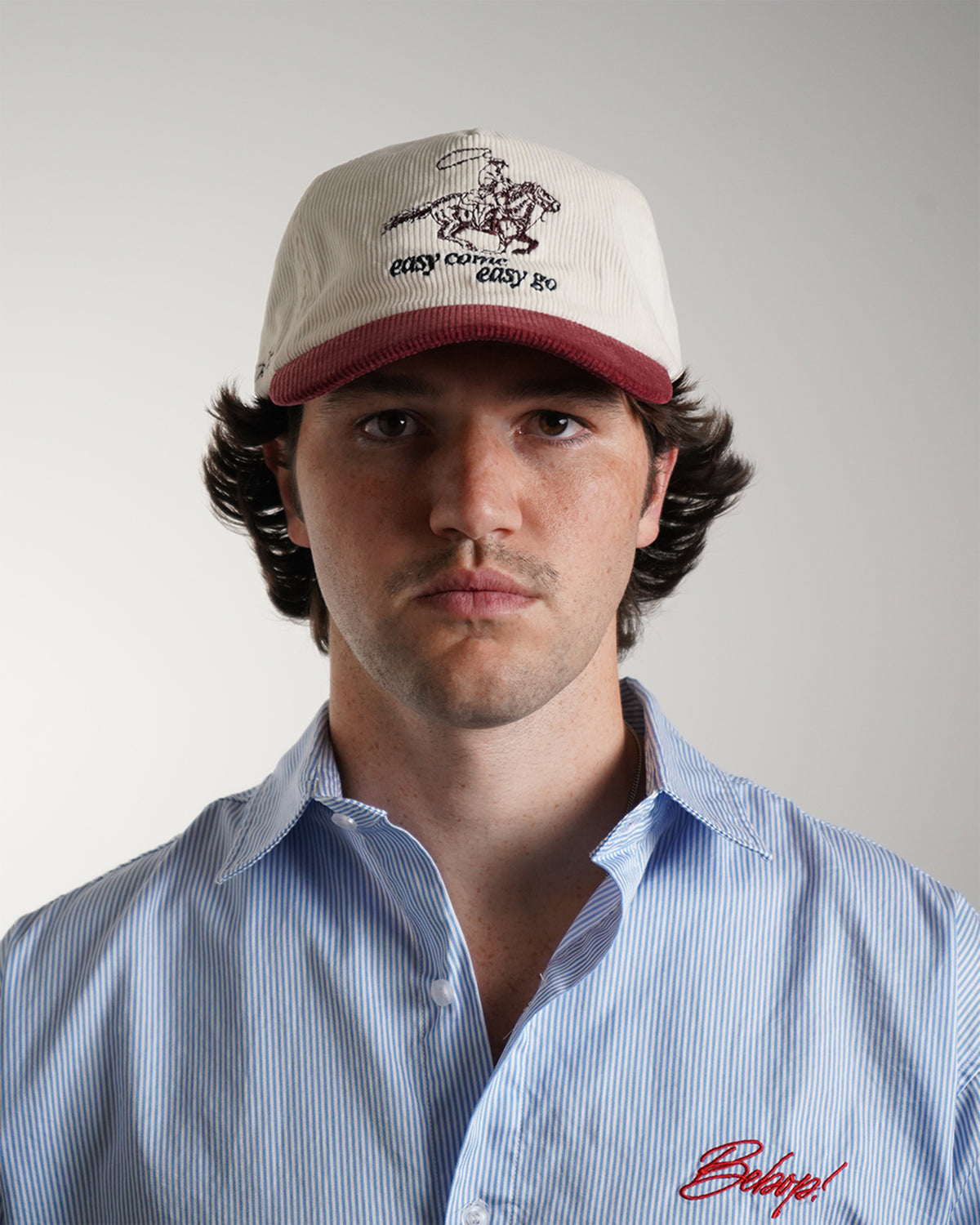Easy Come Easy Go Hat in cream and burgundy with cowboy graphic, front view on model